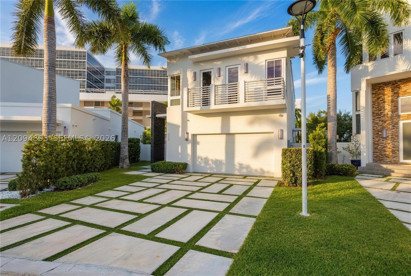 Modern two-story luxury home at 8221 NW 34th Dr in Doral's Oasis neighborhood, with palm trees and a stone paver driveway